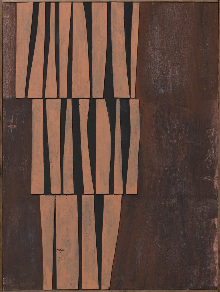 Slats of irregularly shaped wood strips are arranged in a stack on a dark painted wood panel
